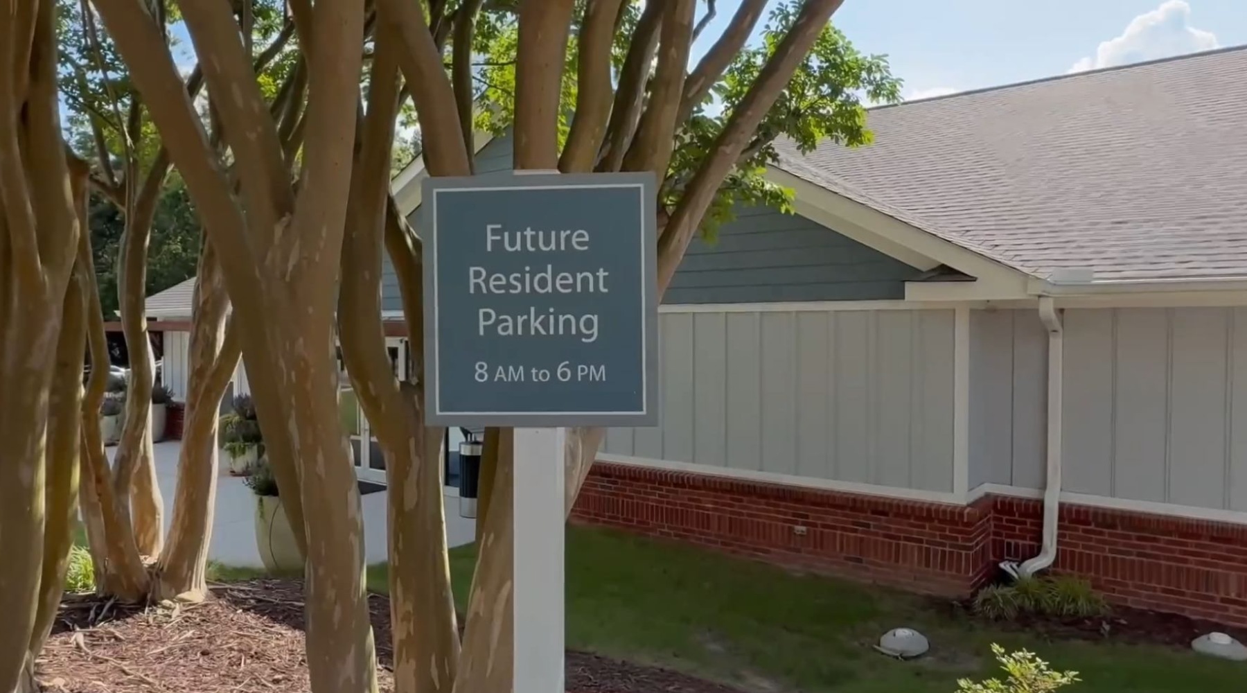 A 'Future Resident Parking' sign sits in front of some trees in an apartment complex.