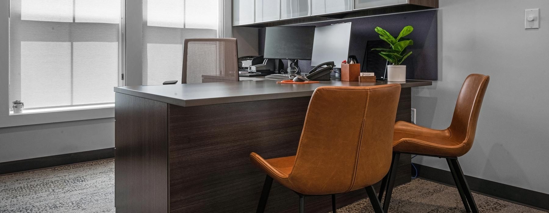 a desk in an office with leather chairs